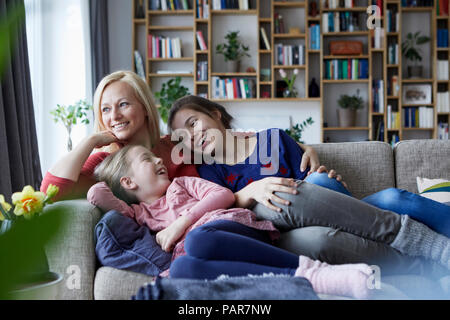 Mutter und ihre Töchter kuscheln und Spaß haben, sitzen auf der Couch Stockfoto