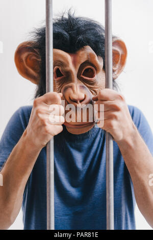 Mann mit Affe Maske hinter Gittern Stockfoto