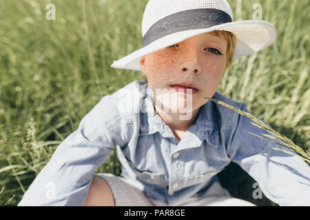 Portrait der Junge mit Hut sitzt im Feld Stockfoto