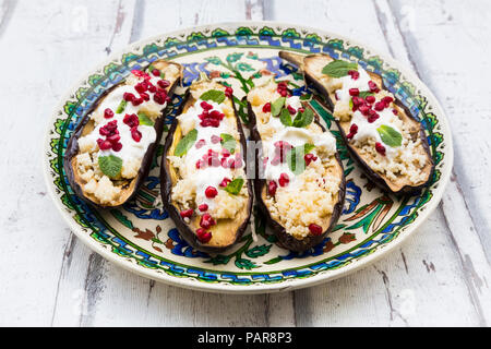 Gefüllte Auberginen mit Couscous, Joghurt Sauce, Minze und Granatapfel Samen Stockfoto