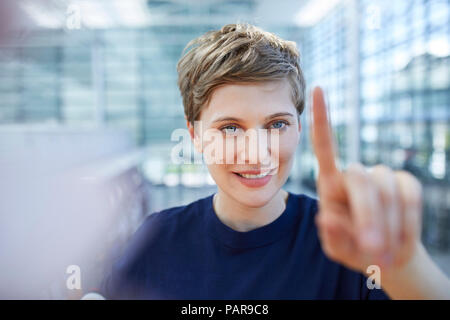 Portrait von blond Geschäftsfrau zu berühren Glasscheibe Stockfoto