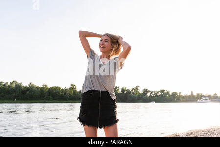 Junge Frau zu Fuß auf Riverside am Abend Stockfoto