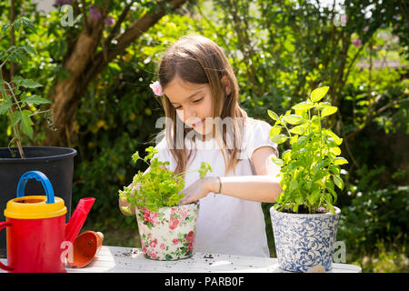 Portrait von kleinen Mädchen Blumenerde Petersilie auf Tisch im Garten Stockfoto