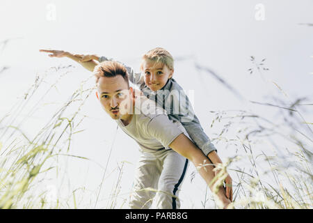 Junger Mann und der Junge in einem Feld vorgibt zu fliegen Stockfoto