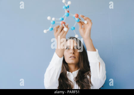 Wissenschaftlerin holding Molekülmodell, suchen Sie nach Lösungen Stockfoto