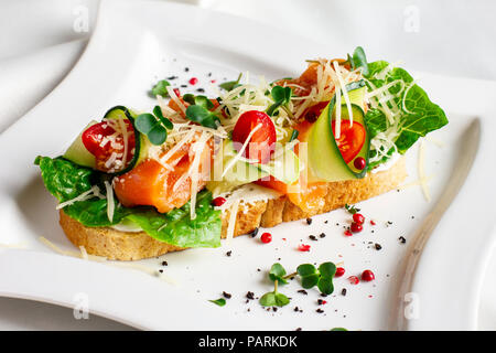 Bruschetta mit Lachs rot Fisch, frischem Gemüse und Kräutern auf einem weißen Teller Stockfoto