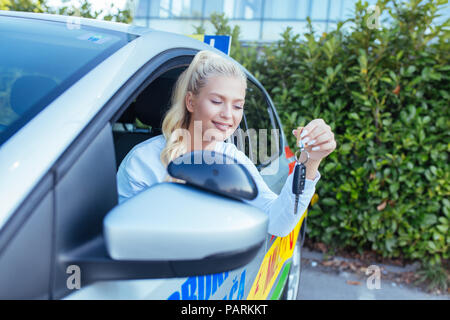 Driving School. Junge Frau in einem Auto sitzen. Treiber sutdent Stolz zeigt die Schlüssel. Freier Platz für Text. Kopieren Sie Platz. Stockfoto