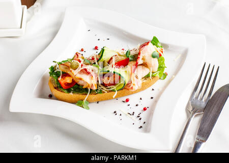 Bruschetta mit Speck, frisches Gemüse und Kapern auf weiße Platte Stockfoto