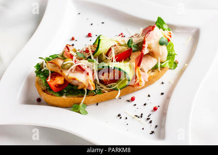 Bruschetta mit Speck, frisches Gemüse und Kapern auf weiße Platte Stockfoto