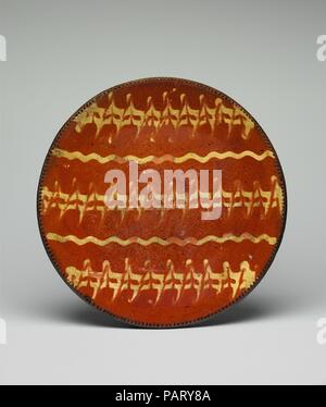 Platte. Kultur: American. Abmessungen: H. 2 1/16-in. (5,2 cm); Durchm. 11 1/2 in. (29,2 cm). Schöpfer: Joseph McCully (American, 1757-1820); Joseph McCully (1771-1857). Datum: Ca. 1800-1850. Die roten Körper dieser Platte war mit einem Gekämmt Design in Creme-farbige Slip dekoriert und mit einem klaren Vorsprung Glasur. Gekämmt slip Dekoration, eine Form von belegschleppen, wurde durch englische Steingut Töpfer begünstigt. Museum: Metropolitan Museum of Art, New York, USA. Stockfoto