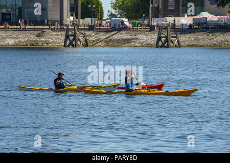 Drei Personen in Kajaks paddeln auf ruhigem Wasser in Cardiff Bay Stockfoto