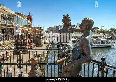 Die bronzeskulptur "Menschen wie wir" auf Mermaid Quay in Cardiff Bay. Ein Beispiel für Kunst im öffentlichen Raum, es besteht aus zwei junge Leute und ein Hund. Stockfoto