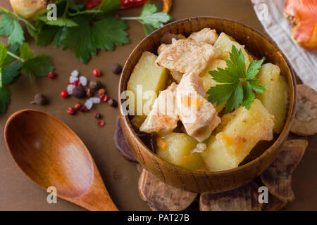 Kartoffeln geschmort mit Hähnchen und Gemüse in eine hölzerne Schüssel Stockfoto