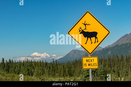 Caribou Crossing Schild mit Denali (Mount McKinley) im Hintergrund, auf einem Highway im Denali National Park, Alaska, USA im Sommer. Stockfoto