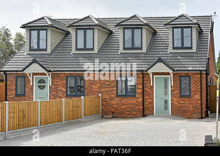 Der neue Doppelhaushälfte home gerade Haus Gebäude über dem vorderen Garten Parkplatz in bestehenden Vorstadtstraße Brentwood Großbritannien gepflastert Stockfoto