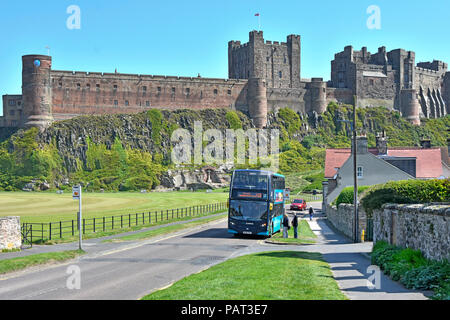 Tourismus & ländliche Double Decker Bus Öffentliche Verkehrsmittel Haltestelle Bamburgh Village Green & historische Bamburgh Castle Northumberland, England Großbritannien Stockfoto