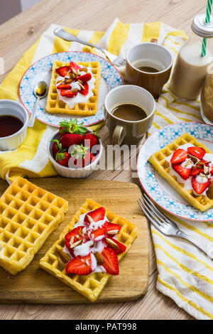 Waffeln, garniert mit Erdbeeren, griechischem Joghurt und Mandeln auf Frühstückstisch Stockfoto