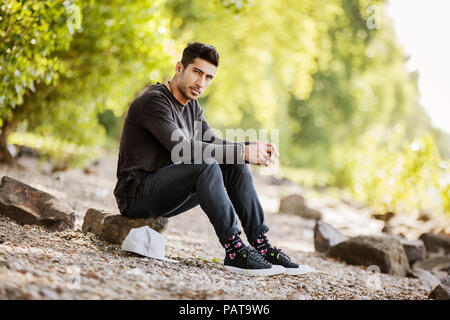 Portrait des jungen Mannes in der Natur sitzen Stockfoto