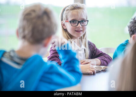 Portrait von lächelnden Schulmädchen mit Mitschülern in der Klasse Stockfoto