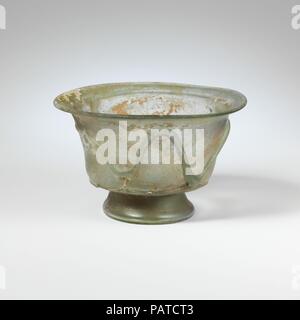 Glasschale. Kultur: Roman. Abmessungen: Insgesamt: 2 5/8 in. (6,7) Andere: 4 1/16-in. (10,3 cm). Datum: 4.Jahrhundert N.CHR.. Transluzent blau grün; Loipen in der gleichen Farbe. Outsplayed rim, mit abgerundeten Lippe; seitlich des Körpers verjüngt sich nach unten, dann Kurven nach innen; groß, gespreizte tubular Fuß, mit Falten; Dick, konischer Boden, in der Mitte von pontil Mark abgeflacht. Eine feine Spur angewendet wird horizontal auf der Unterseite der Seite; ein weiterer dicker Trail angewendet wird über Sie und die Wunde, die runde Seite in einem unregelmäßigen, geschwungenen Zick-Zack-Muster, einer langen Trail unter Rim. Intakt; pinprick Blasen und blasen Streifen, mit Stockfoto