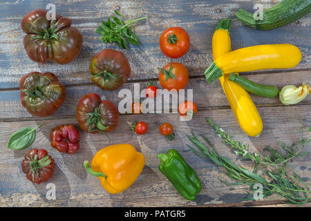 Gruppe von Tomaten, alte Sorten von verschiedenen Tomaten auf hölzernen boarc über eine alte bemalte Wand Hintergrund Stockfoto