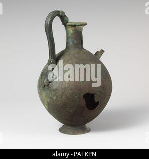 Bronze Kanne. Kultur: Zypriotische. Abmessungen: H. 8 7/8 in. (22,5 cm). Datum: Ca. 6. Jahrhundert v. Chr.. Die endet oben in einer Schlange Kopf Griff, Unten in der Maske eines Löwen. Der Löwe Motiv sowie der Maul- und der Vase sind typisch Griechisch, während die Form der Kanne Zyperns ist, was darauf hindeutet, dass das Stück kann von einem griechischen Handwerker arbeiten auf Zypern gemacht wurden. Museum: Metropolitan Museum of Art, New York, USA. Stockfoto
