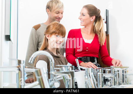 Porträt einer glücklichen Familie auf der Suche nach einem neuen Badezimmer Waschbecken Wasserhahn Stockfoto
