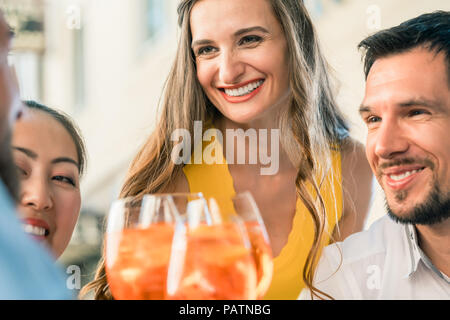 Schöne Frau und ihre besten Freunde Toasten mit einem erfrischenden Getränk Stockfoto