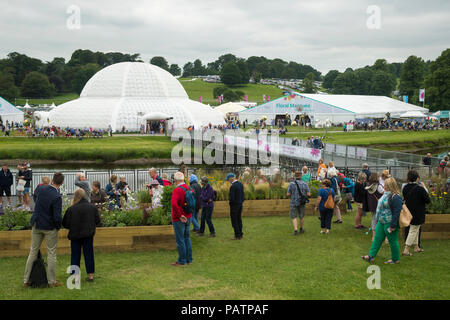 An der RHS Chatsworth Flower Show (Besucher durch Exponate, Festzelt, grosser Wintergarten Dome, Fluss & provisorische Brücke) Derbyshire, England, UK Showground. Stockfoto