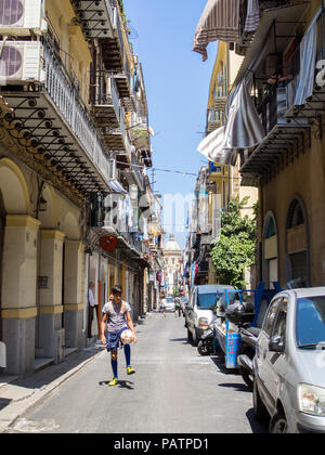 Ein junger Mann spielt mit einem Fußball in einer Seitenstraße, Palermo, Sizilien. Stockfoto