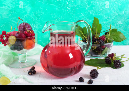 Grütze. Obst vitamin Drink in einer Glaskanne und Reife frische Beeren auf einem hellen Hintergrund. Stockfoto