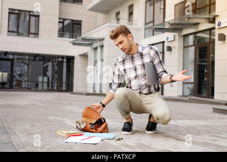 Junge Mann an der Bücher auf dem Boden suchen umgekippt Stockfoto