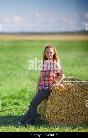 Junge cute Teen Girl posiert in der Nähe von einem Heuschober im Feld. das ländliche Leben Stockfoto