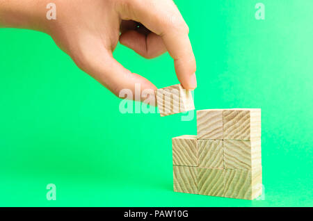 Holzklötze und der Geschäftsmann Hand. Konzept von Immobilien Bau. Hand des Architekten hält einen Holzklotz als Teil des Hauses. Projekt der Stockfoto