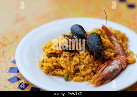 Royal Paella. Lecker Reis mit Garnelen, Muscheln und Zitrone auf weiße Platte Stockfoto