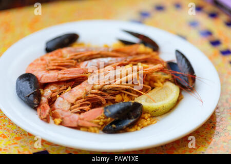 Royal Paella. Lecker Reis mit Garnelen, Muscheln und Zitrone auf weiße Platte Stockfoto