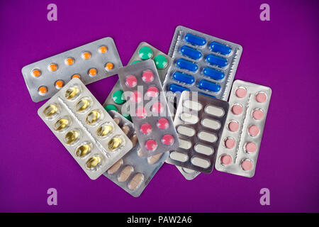 Die Gruppe der Farbe medizinische Pillen in Pakete auf lila Hintergrund. Apotheke, Drogerie Stockfoto