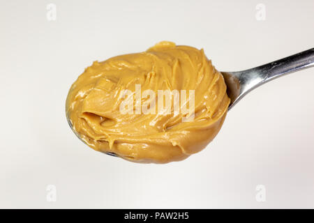 Ein Wirbel von Erdnußbutter auf einem Löffel über auf ein Brot zu verbreiten. Stockfoto
