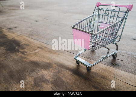 Klein Warenkorb ist leer Einkaufswagen auf Holzboden. Stockfoto