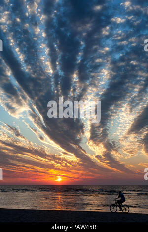 Mann auf dem Fahrrad entlang der Strand bei Sonnenuntergang mit einem sehr ungewöhnlichen Wolken. Ostsee Stockfoto