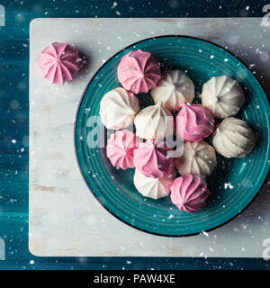 Pastellfarben rosa und weiß Baiser auf grünem Hintergrund. Weihnachten Magic Snow Fall Stockfoto