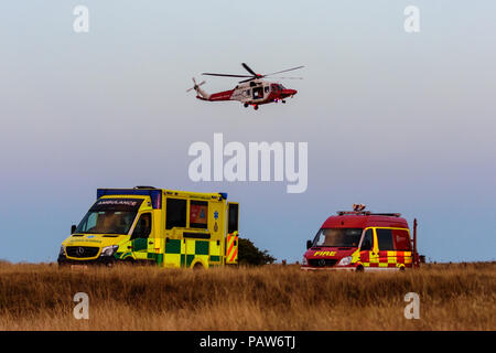 Westbury, Wiltshire, UK, 24. Juli 2018, Coast Guard Hubschrauber über Krankenwagen und Feuerwehr van Einsatzfahrzeuge. Nehmen Sie vor dem winching Besatzungsmitglied auf verletzte Gleitschirm credit Estelle Bowden/Alamy leben Nachrichten Stockfoto