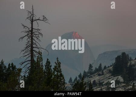 Yosemite Nationalpark, Kalifornien, USA. 24. Juli, 2018. Dienstag, 24. Juli 2018. Das letzte bisschen Sonnenlicht reflektiert iconic Granit verfügen über Yosemite National Park, Half Dome, wie aus der Olmsted Point vista Aussichtspunkt gesehen. Half Dome ist in Rauch aus der Ferguson Feuer umgeben, Brennen in der Nähe des Park El Portal Eingang. Credit: Tracy Barbutes/ZUMA Draht/Alamy leben Nachrichten Stockfoto