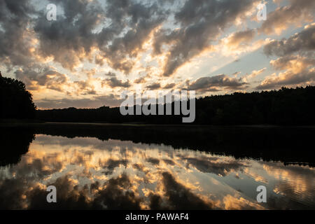 Deutschland, Berlin. 25. Juli, 2018. Die Sonne steigt über Grunewaldsee hinter Wolken. Credit: Paul Zinken/dpa/Alamy leben Nachrichten Stockfoto