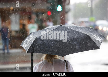 Hamburg, Deutschland. 25. Juli, 2018. Eine Frau steht an einer Ampel mit einem Regenschirm während einer kurzen Regendusche. Credit: Bodo Marks/dpa/Alamy leben Nachrichten Stockfoto