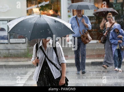 Hamburg, Deutschland. 25. Juli, 2018. Passanten eine Straße Regenschirme während eine schnelle Dusche. Credit: Bodo Marks/dpa/Alamy leben Nachrichten Stockfoto