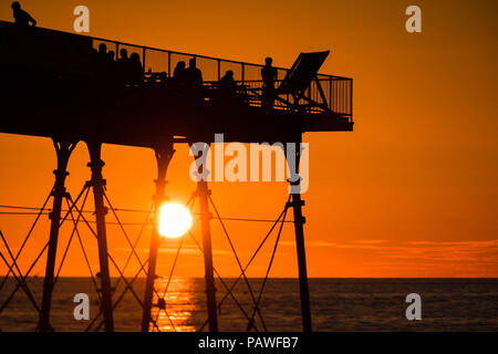 Aberystwyth Wales UK, Mittwoch, 25. Juli 2018 UK Wetter: die Menschen werden durch den herrlichen Sonnenuntergang über Aberystwyth Pier Silhouette am Ende eines Tages des heißen Sommer Sonnenschein. Großbritannien große Hitzewelle fort, mit wenig Erholung von der sehr trockenen Wetter trotz etwas Regen in der Prognose für das Wochenende Foto: Keith Morris/Alamy leben Nachrichten Stockfoto