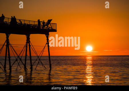 Aberystwyth Wales UK, Mittwoch, 25. Juli 2018 UK Wetter: die Menschen werden durch den herrlichen Sonnenuntergang über Aberystwyth Pier Silhouette am Ende eines Tages des heißen Sommer Sonnenschein. Großbritannien große Hitzewelle fort, mit wenig Erholung von der sehr trockenen Wetter trotz etwas Regen in der Prognose für das Wochenende Foto: Keith Morris/Alamy leben Nachrichten Stockfoto