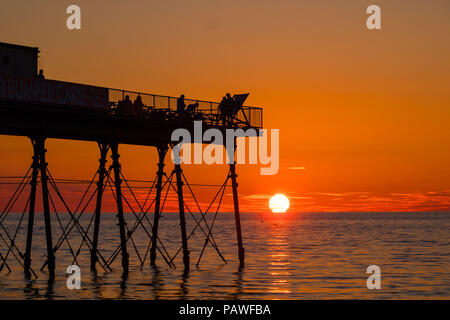 Aberystwyth Wales UK, Mittwoch, 25. Juli 2018 UK Wetter: die Menschen werden durch den herrlichen Sonnenuntergang über Aberystwyth Pier Silhouette am Ende eines Tages des heißen Sommer Sonnenschein. Großbritannien große Hitzewelle fort, mit wenig Erholung von der sehr trockenen Wetter trotz etwas Regen in der Prognose für das Wochenende Foto: Keith Morris/Alamy leben Nachrichten Stockfoto