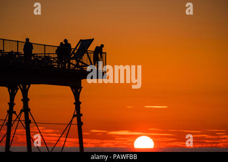 Aberystwyth Wales UK, Mittwoch, 25. Juli 2018 UK Wetter: die Menschen werden durch den herrlichen Sonnenuntergang über Aberystwyth Pier Silhouette am Ende eines Tages des heißen Sommer Sonnenschein. Großbritannien große Hitzewelle fort, mit wenig Erholung von der sehr trockenen Wetter trotz etwas Regen in der Prognose für das Wochenende Foto: Keith Morris/Alamy leben Nachrichten Stockfoto